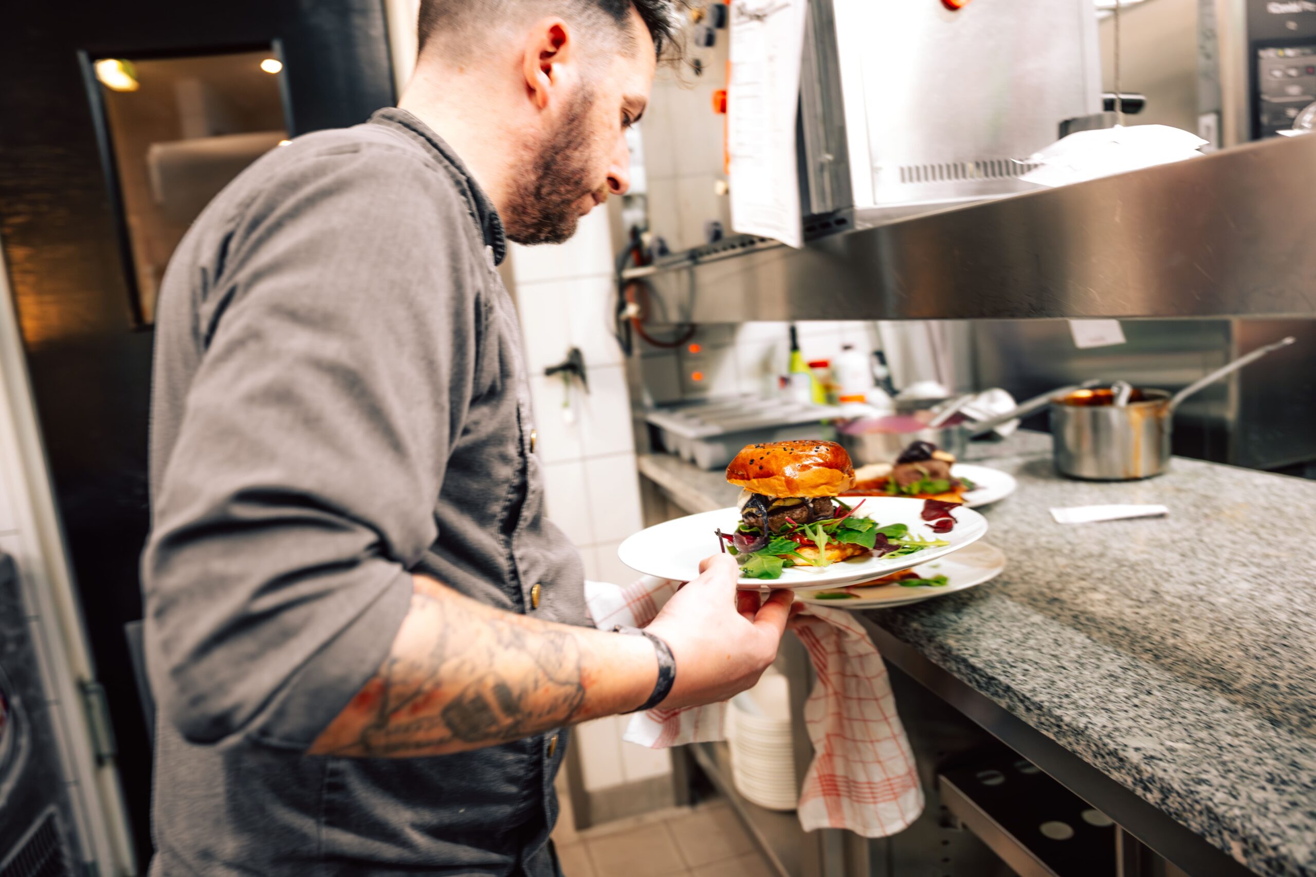 Koch trägt Teller mit Porthhof Burger